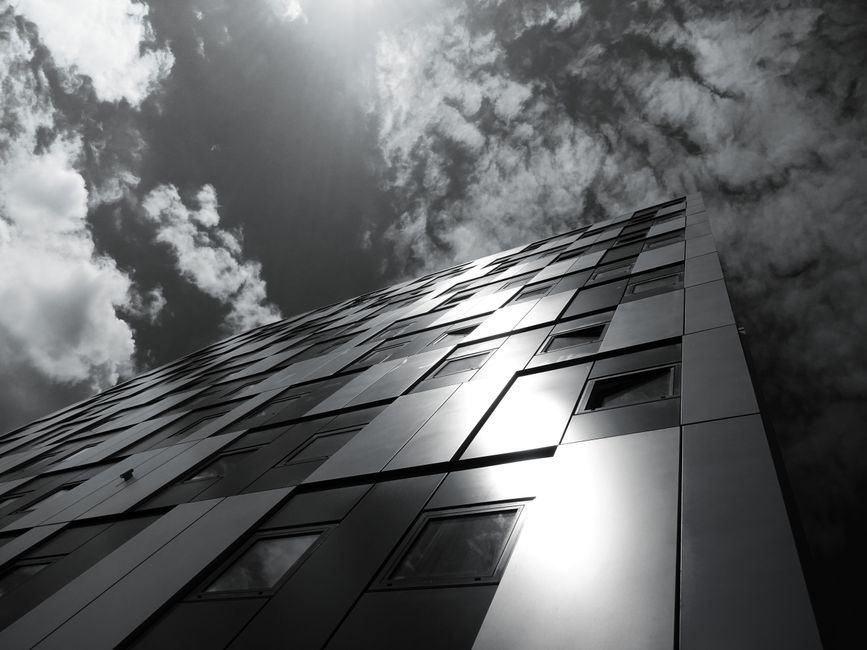 Vista de ángulo bajo de un edificio moderno reflejando el cielo nublado