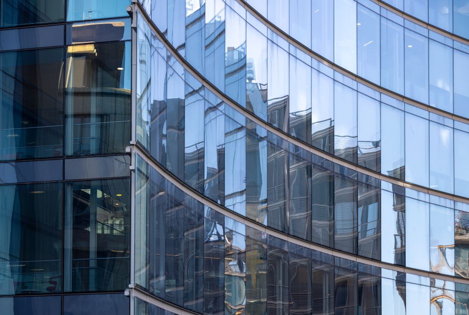 Fachada de vidrio curva reflejando edificios circundantes