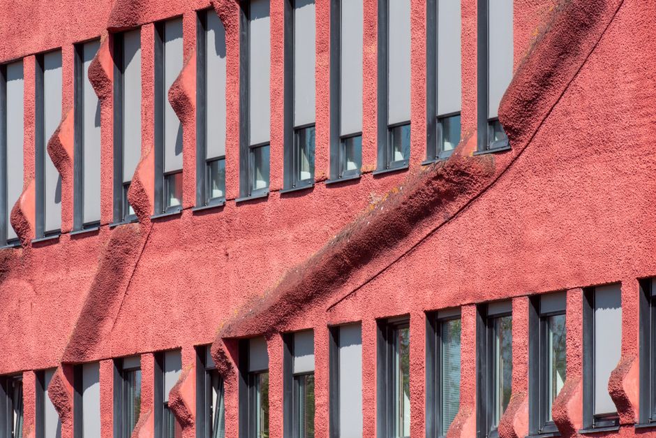 Fachada de edificio con textura roja distintiva y ventanas múltiples