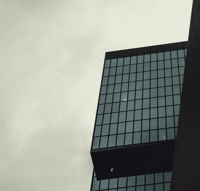 Vista de bajo ángulo de un rascacielos moderno con fachada de vidrio contra un cielo nublado